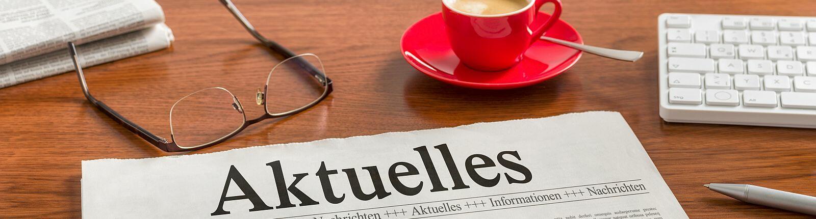 Brille liegt neben der Zeitung auf der Aktuelles steht