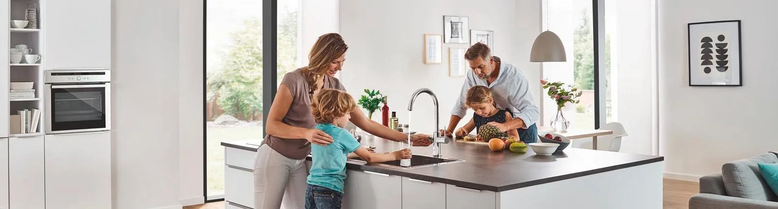 Familie steht an der Kochinsel und nimmt Leitungswasser