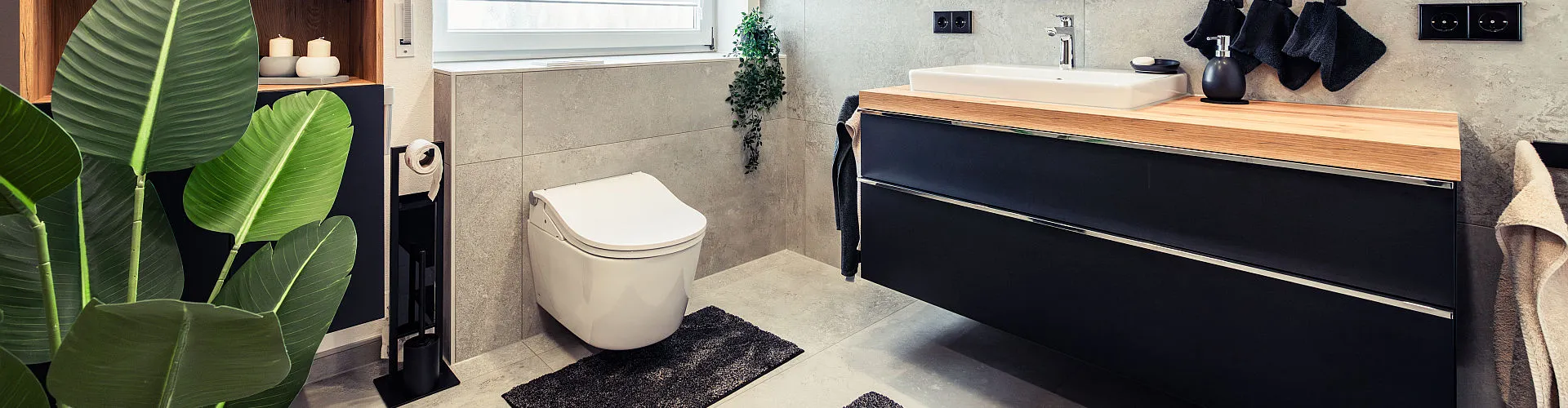 Ein modernes Badezimmer mit minimalistischer Einrichtung zeigt ein wandmontiertes Dusch-WC vor hellgrauen Fliesen.