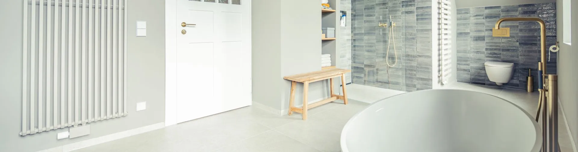 Blick ins Premium-Bad mit freistehender Badewanne und champagner-goldener Armatur.