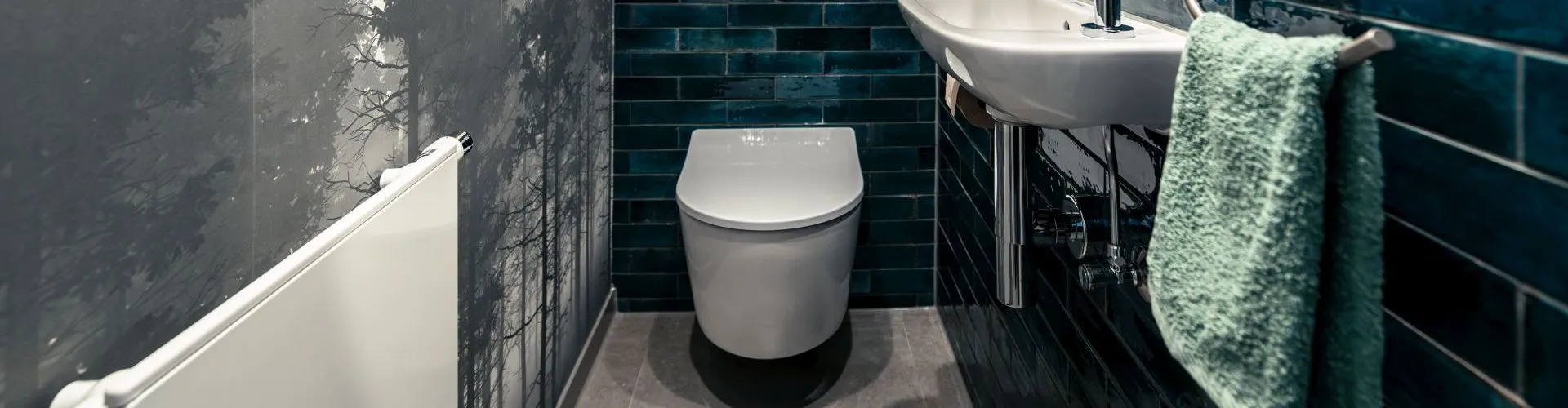 Gäste-WC mit dunklen, glänzenden Fliesen in tiefem Blau und einer minimalistischen Ausstattung.