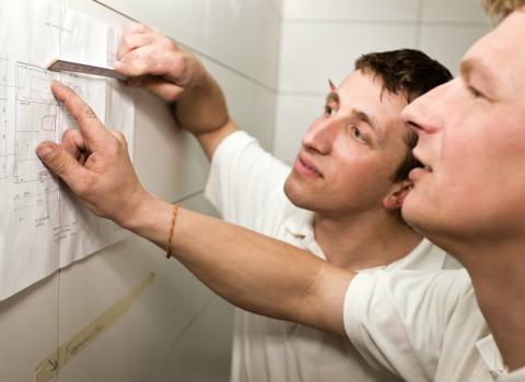 Mitarbeiter besprechen einen Grundriss bei der Installation eines Badezimmers.