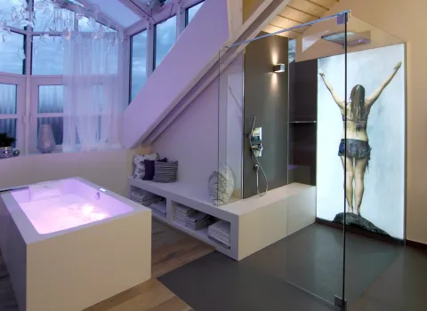 Whirlwanne mit LEDs und Dusche mit hinterleuchtetem Wandbild.