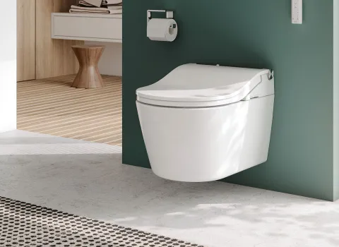 Ein modernes Badezimmer mit einem wandhängenden TOTO-Washlet, das vor einer grünen Wand montiert ist. 