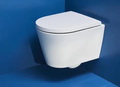 Eine schwebende weiße Toilette ist an einer tiefblauen Wand montiert, wodurch sie modern und minimalistisch wirkt.