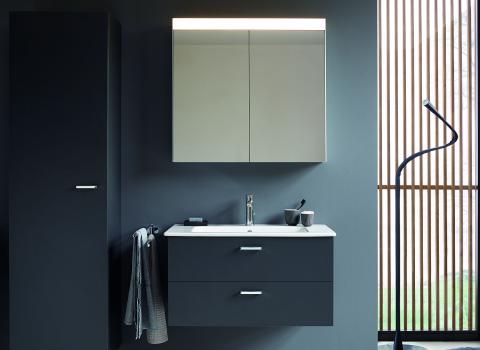 Grauer Duravit XBase Waschtisch mit Spiegelschrank, Handtuch und Badutensilien in minimalistischem Badezimmerdesign.