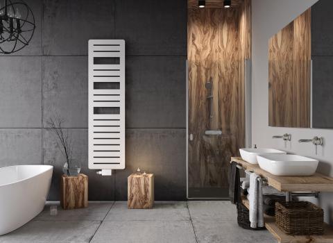 Ein modernes Badezimmer im Industrial-Stil mit Betonwänden und Holzakzenten. Eine freistehende weiße Badewanne steht links neben einem weißen, vertikal montierten Design-Heizkörper.