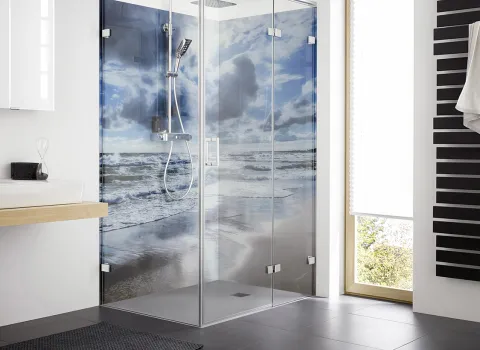 Duschkabine HSK Atelier Plan mit Glaswänden und Strandmotiv im modernen Bad. Der Raum hat einen schwarzen Handtuchheizkörper und ein großes Fenster für viel Licht.