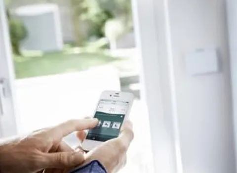 Ein Mann betätigt sein Heizsysteme über Smart Home am Handy. 