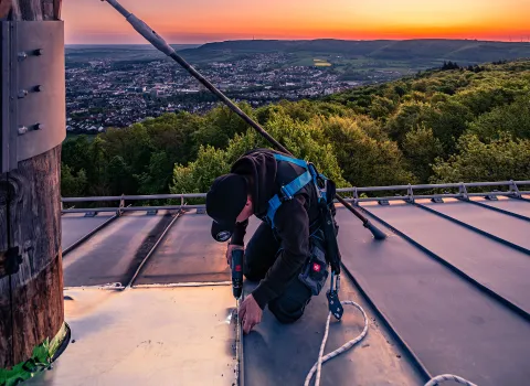 Ein Flaschner von Vitus König montiert eine Metallplatte auf dem Dach am Aalbäumle.