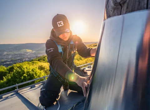 Ein Flaschner von Vitus König montiert einen Metallschutz am Baumstamm.