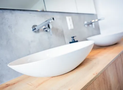 Nahaufnahme Doppelwaschtisch mit zwei Aufsatzbecken auf maßgefertigtem Holz-Unterschrank.