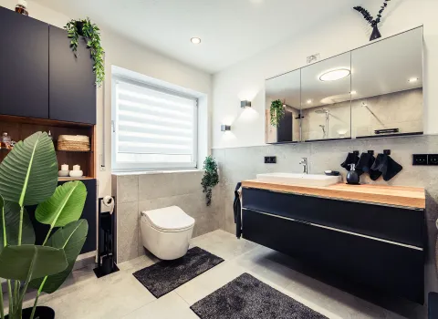 Das Bild zeigt ein stilvolles Designer-Badezimmer mit hochwertigen Materialien wie Holz, Betonoptik und mattschwarzen Oberflächen.