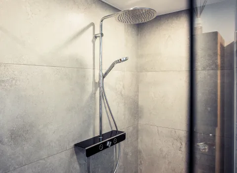 Nahaufnahme einer Duscharmatur mit Regenduschkopf und multifunktionaler Handbrause in einem modernen Badezimmer.