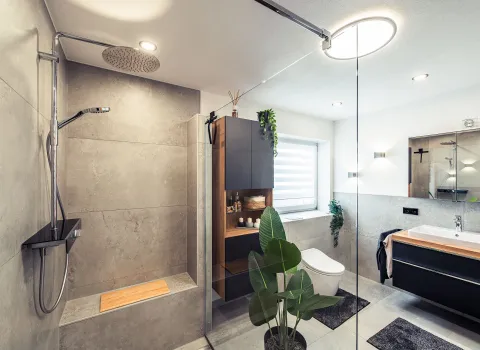 Ein luxuriöses Badezimmer mit offener Walk-In-Dusche, wandhängendem WC und stilvollem Waschtisch mit Holzplatte. Die Dusche ist mit großformatigen Fliesen in Betonoptik und einer integrierten Sitzbank ausgestattet.