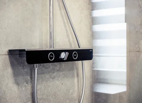 Detailaufnahme einer modernen Duschsteuerung mit mattschwarzer Oberfläche und silbernen Bedienelementen.