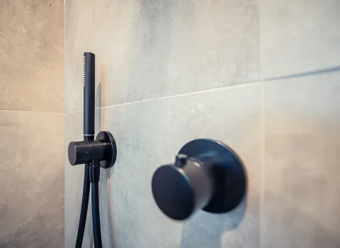 Nahaufnahme einer Duscharmatur mit flexibler Handbrause in Schwarz matt.