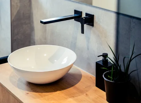 Detailaufnahme eines modernen Waschtisch-Schale mit matter scharzer Wandarmatur.