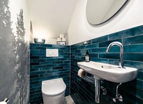 Kleines Badezimmer in Schlauchform mit Dachschräge und blauen Fliesen.