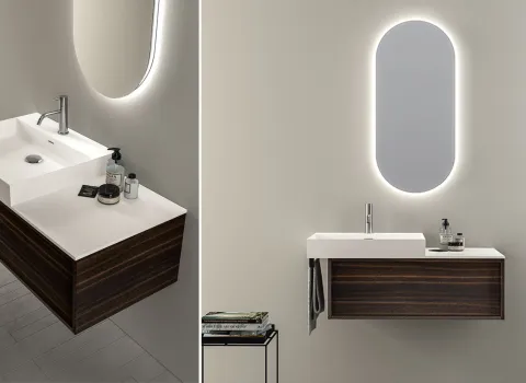 Doppelansicht eines eleganten Badezimmers von Stocco mit dunkel gemasertem Unterschrank, weißer Waschtischplatte und beleuchtetem Ovalspiegel.