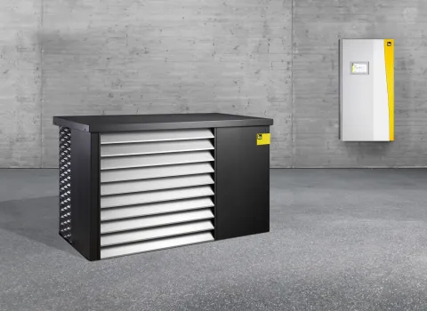 Innen- und Außeneinheit der Wärmepumpe iDM AERO ALM 2-8 und 4-12 in einem leeren, grauen Raum.