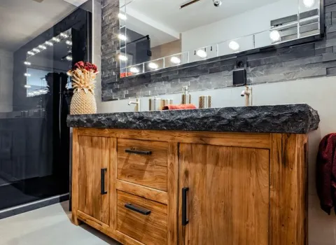 Rustikaler Holzwaschtisch mit massiver Natursteinplatte in modernem Badezimmer.