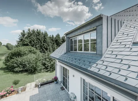 Modernes Bauernhaus mit Dachgiebel und Alubedachung.