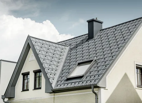 Massives Einfamilienhaus mit mehrstufigen Spitzdach mit Aluverkleidung von Prefa.