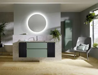 Ein tagesllichthelles Badezimmer mit einer hellgrünen, wandhängenden Waschtisch-Einheit und einem großen, runden Spiegel mit LED-Beleuchtung an der Wand. 