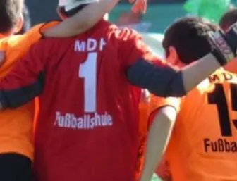MDH Fußballspieler von hinten mit rotem und orangenen Trikots.