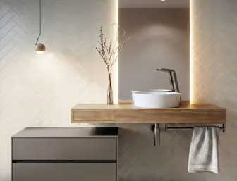 Echtholz-Waschtisch mit schwebendem Unterschrank und auffaelligem, rundem Waschbecken. Dezente Beleuchtung und geometrische Fliesen setzen Akzente.