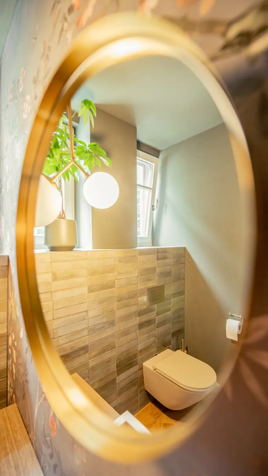 Das Bild zeigt einen Ausschnitt eines stilvollen Badezimmers, eingefangen durch den Rand eines runden Badezimmerspiegels.