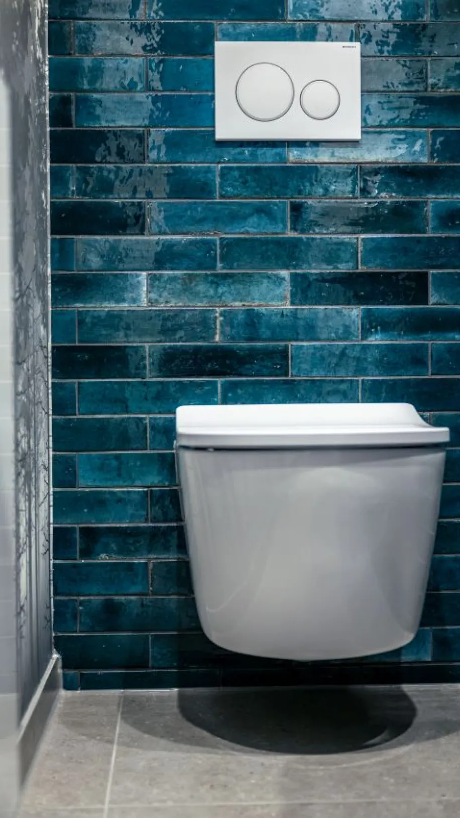 Massives WC mit leicht gebogenen Deckel vor blauen Fliesen in urban-Look.