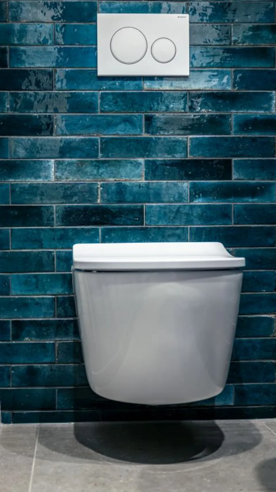 Massives WC mit leicht gebogenen Deckel vor blauen Fliesen in urban-Look.