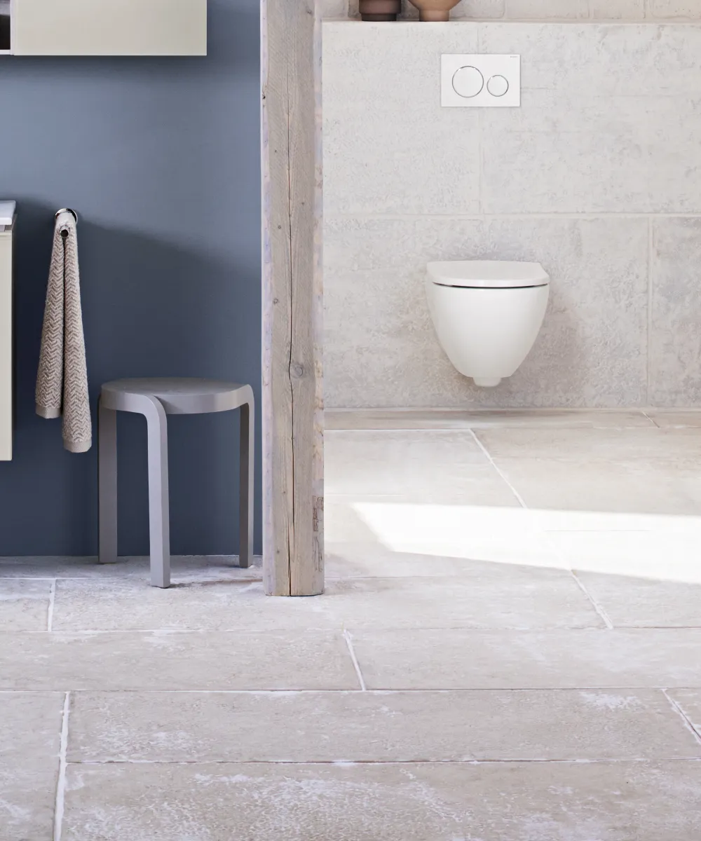 Ein modernes Badezimmer mit minimalistischen, hellen Möbeln vor einer dunkelblauen Wand.