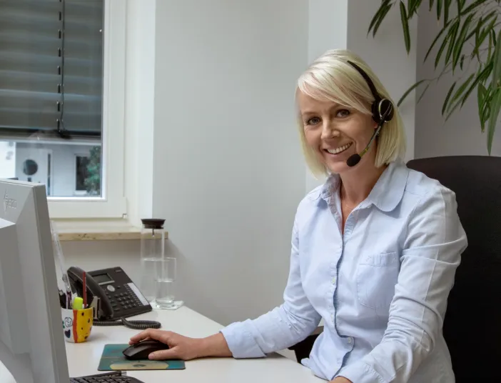 Bürokauffrau mit Headset in einem SHK-Handwerksbetrieb.