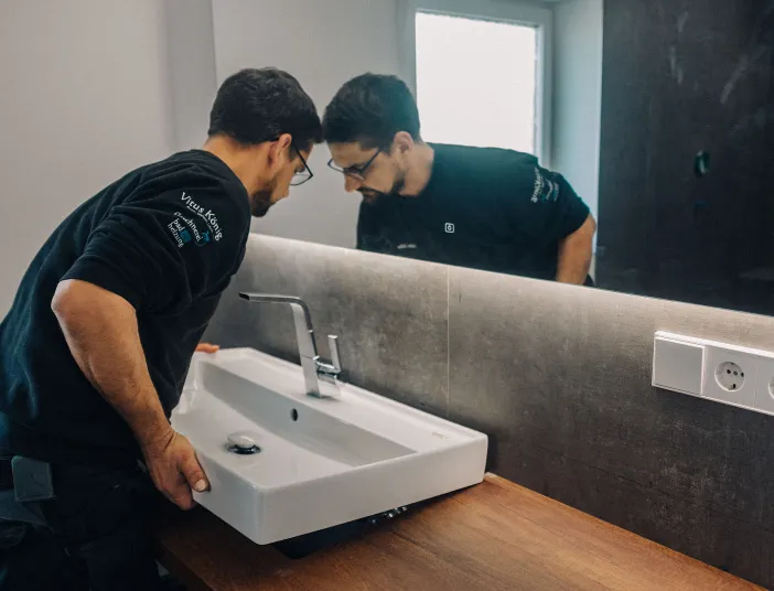 Anlagenmechaniker SHK montiert ein Waschbecken.