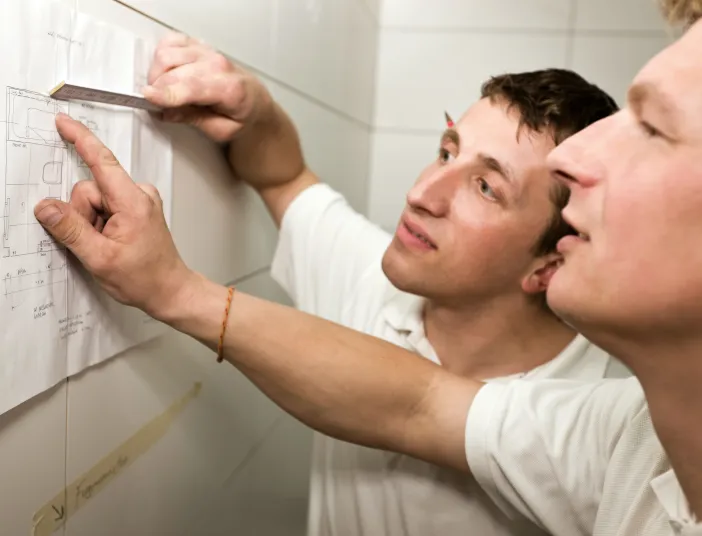 Mitarbeiter besprechen einen Grundriss bei der Installation eines Badezimmers.