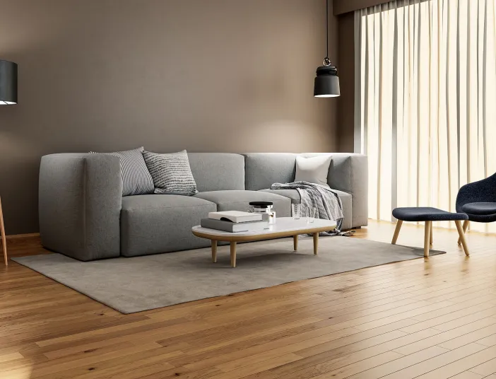 Helles Wohnzimmer mit Holzfußboden, grauem Ecksofa und Designer-Sessel. Der glatte, neutrale Innenputz hebt die elegante Einrichtung hervor.