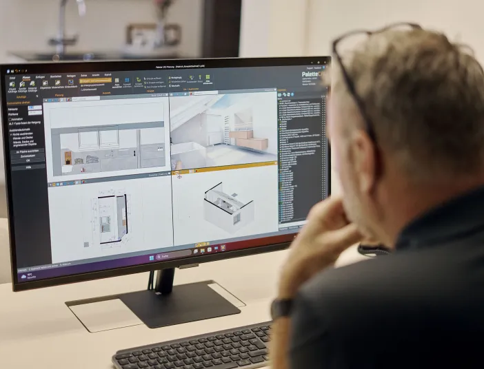 Ein Badplaner betrachtet auf einem Computerbildschirm detaillierte 3D-Modelle und Grundrisse eines Badezimmers. Er arbeitet an der digitalen Planung zur optimalen Beratung.