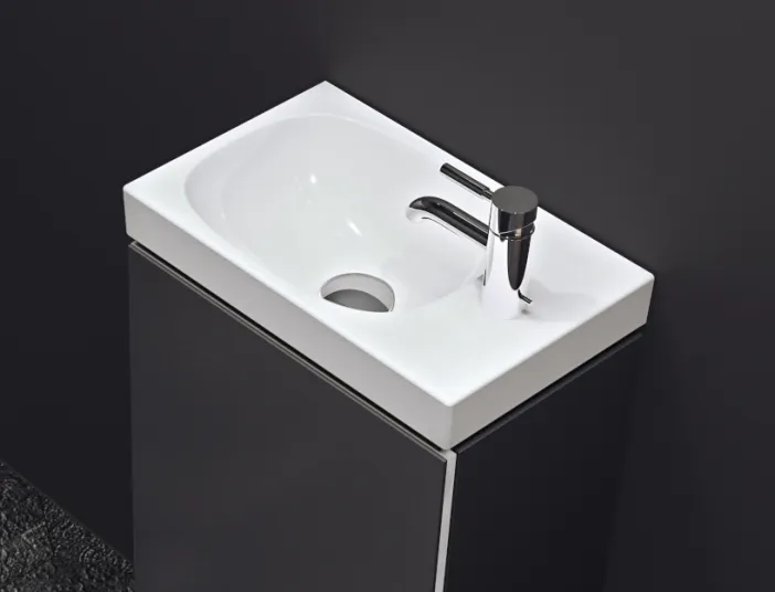 Ein kleines, rechteckiges Waschbecken in modernem Design mit einem glänzenden Chrom-Wasserhahn.