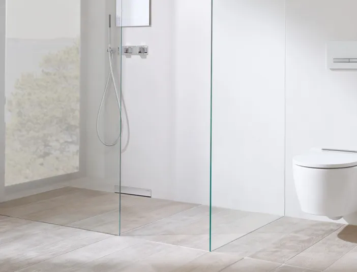 Ein modernes, minimalistisches Badezimmer mit einer bodenebenen Dusche und einer gläsernen Duschabtrennung.