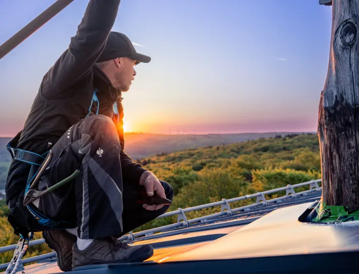 Ein Flaschner von Vitus König hockt auf einem Dach und blickt gen Horizont.