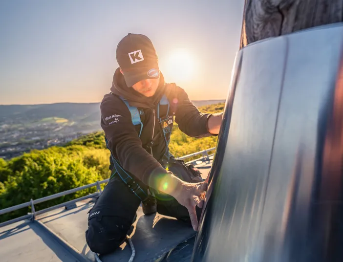 Ein Flaschner von Vitus König montiert einen Metallschutz am Baumstamm.