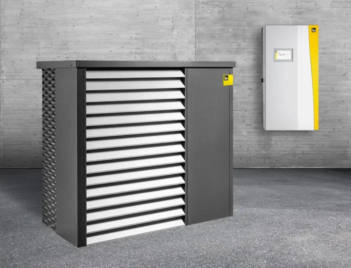 Außen- und Inneneinheit der Wärmepumpe AERO ALM 6-15 in einem grauen Lagerraum.
